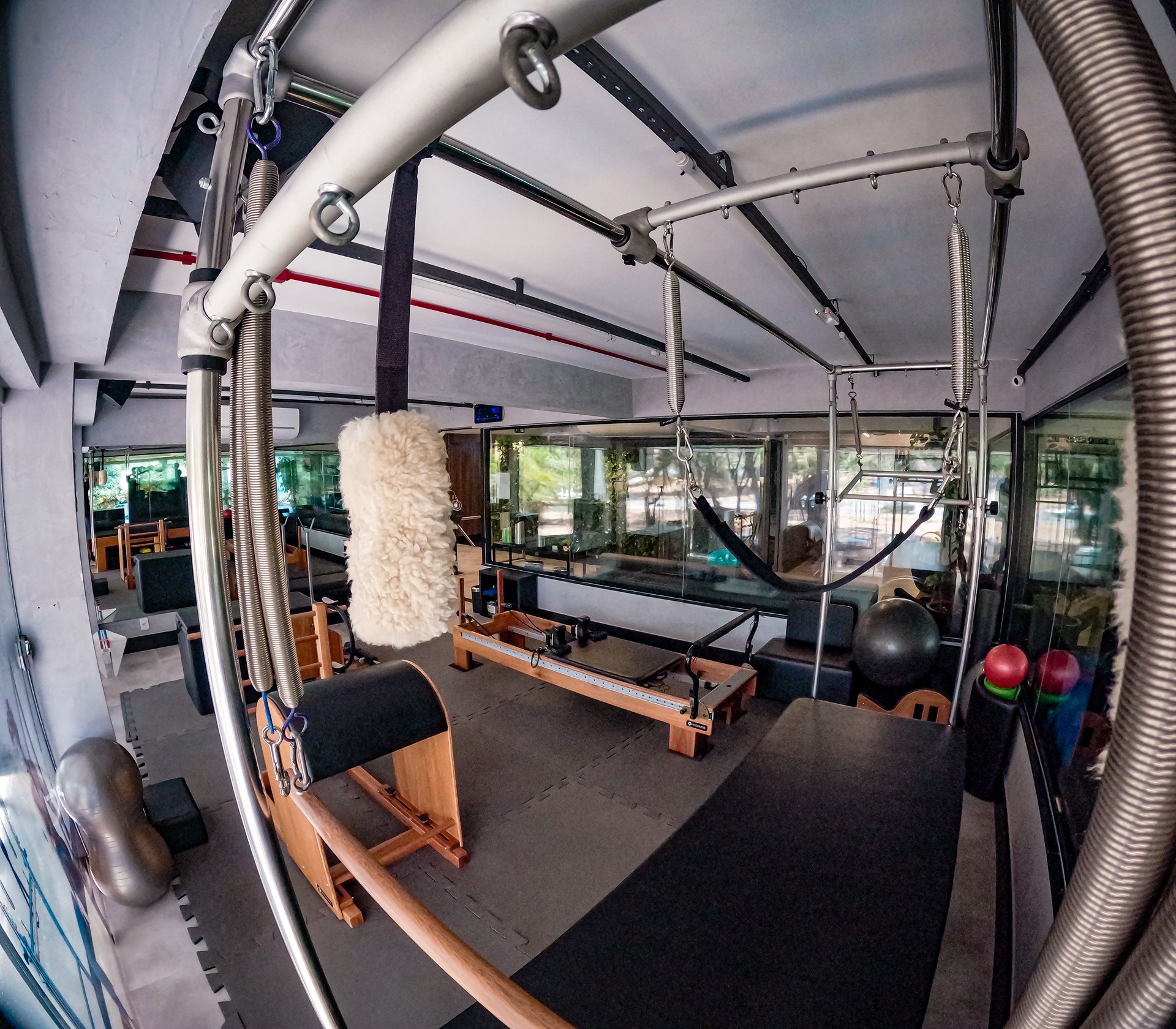 Sala do studio com Cadillac, reformer e bolas de exercício ao lado de amplas janelas